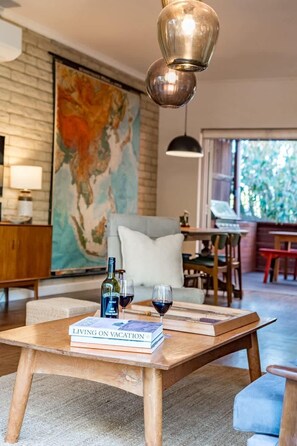 Una sala de estar acogedora con una mesa de centro de madera, libros, copas de vino y un globo terráqueo.