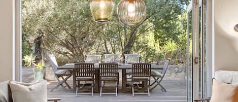 A deck with a table and chairs, a sofa, and a hanging light fixture.