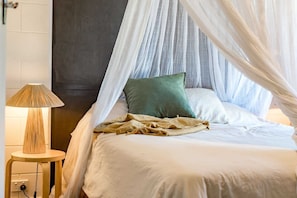 Een bed met hemelbed, een bedlampje en een stopcontact.