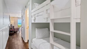 Una habitación con literas, vistas al mar y un pasillo con una mesa y sillas.