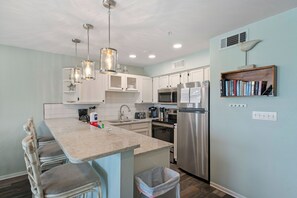 A modern kitchen with white cabinets, stainless steel appliances, and a central island with bar stools.
