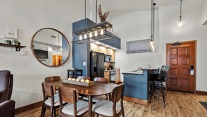 A modern kitchen with a blue accent wall, wooden dining table, and chairs. - Mountain Retreat with A+ Location and Resort Amenities – Timberline Lodge 2309! (Steamboat Springs)