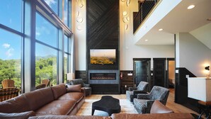 Amplia sala de estar con sofás de cuero, chimenea y una gran pantalla de televisión.