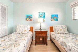A room with two beds, a nightstand, and wall art depicting underwater scenes.
