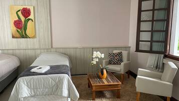 Two single beds with white bedding, a coffee table, and a comfortable armchair.