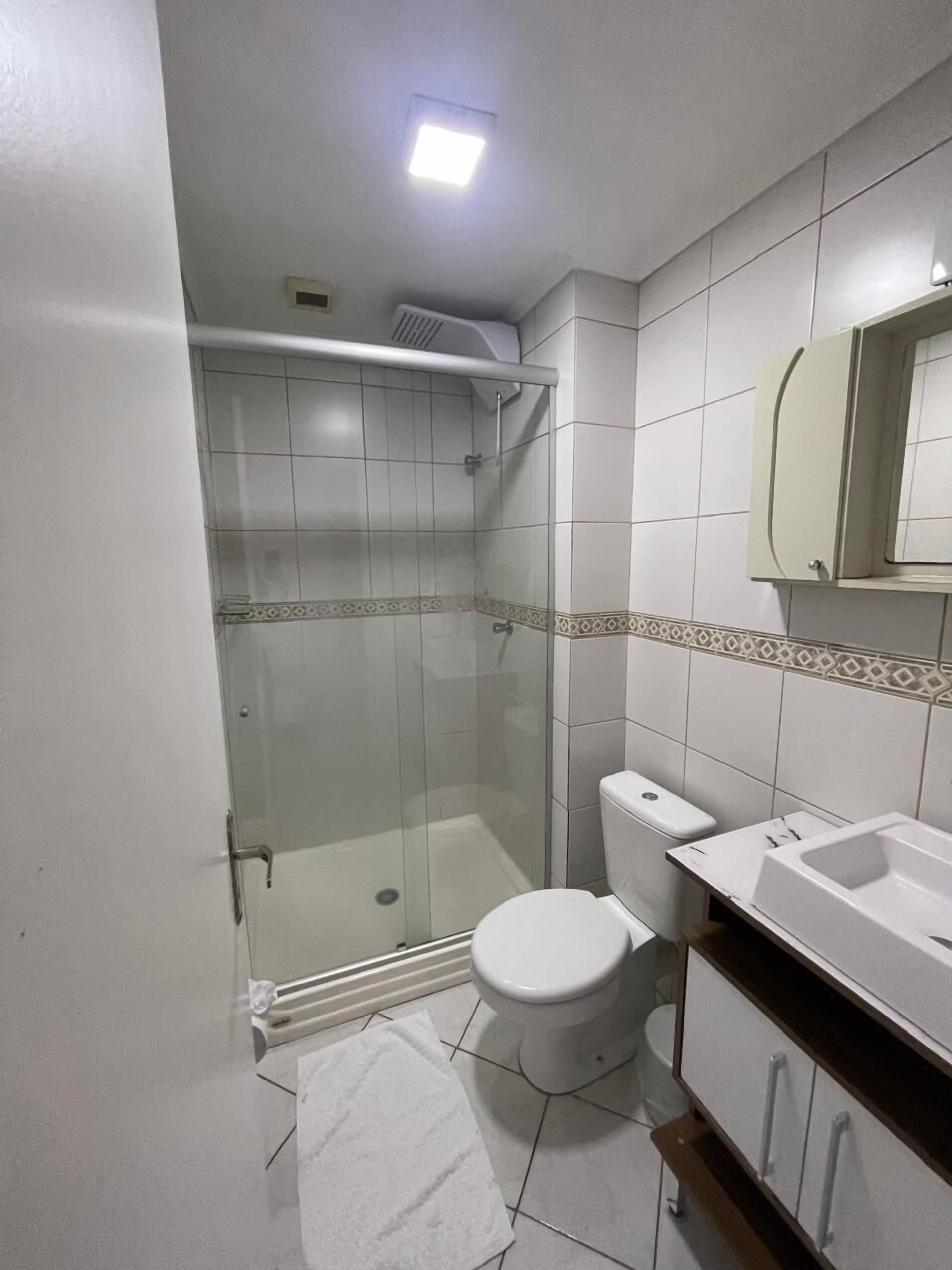 Un baño pequeño con inodoro, lavabo y ducha.