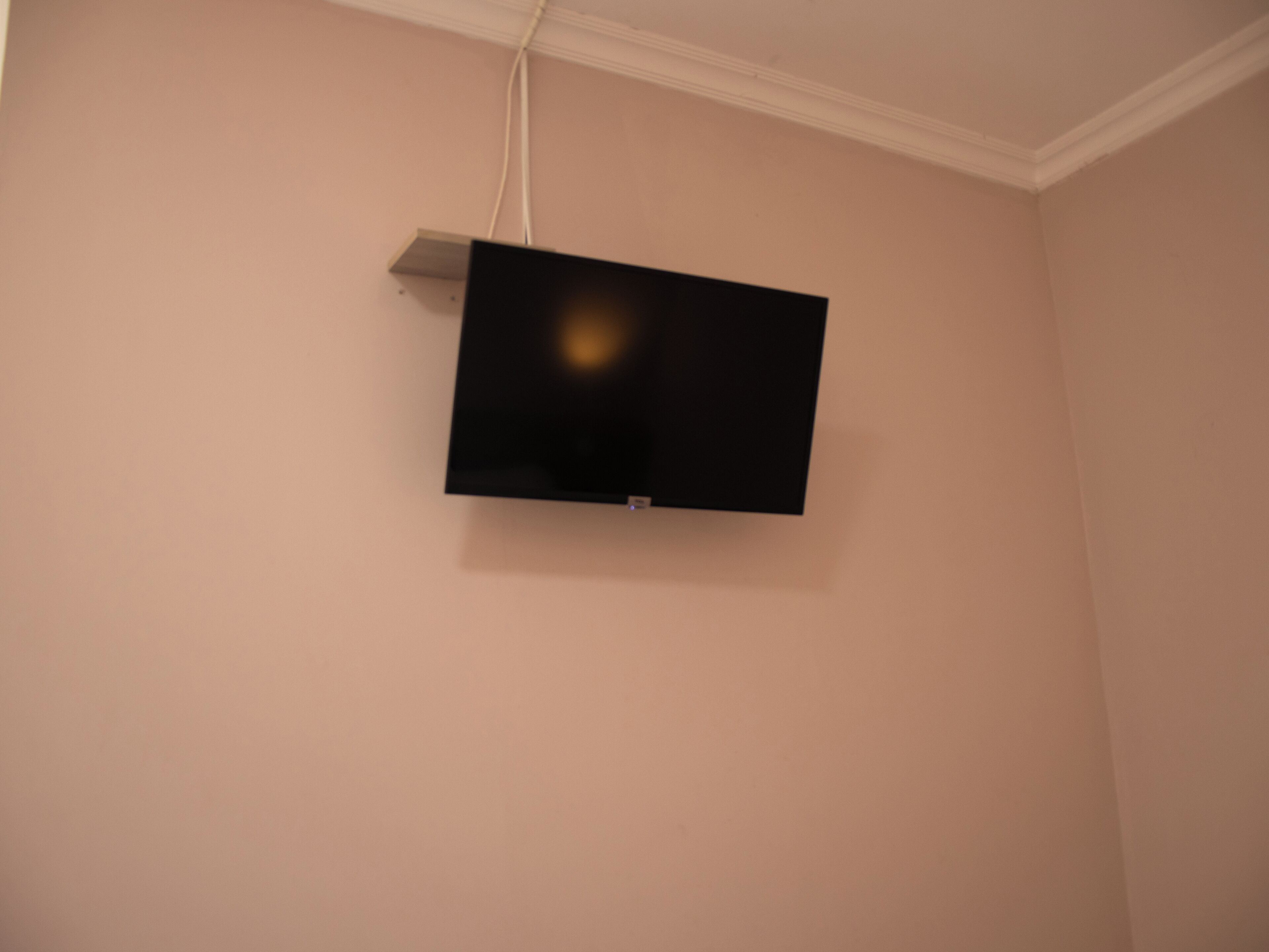 A flat-screen TV mounted on a wall in a room with a plain, light-colored wall.