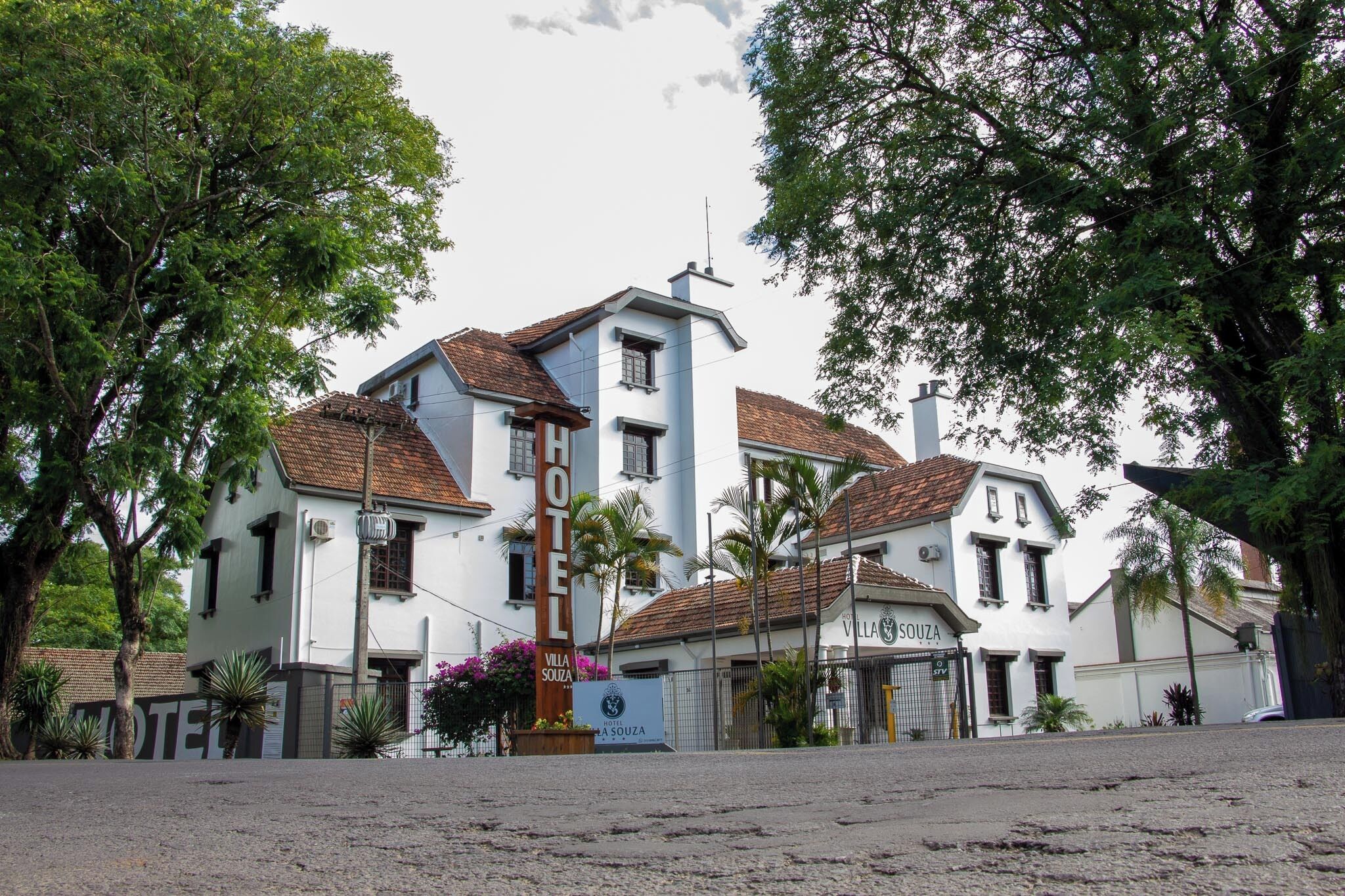 A hotel with a white facade, multiple windows, and a tiled roof.