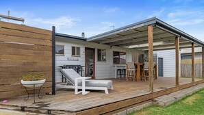 A covered patio area with a grill, outdoor seating, and a wooden deck. - Surf Beach Retreat, 200 mtrs from Surf Beach, family holiday games, free WiFi (Surf Beach)