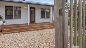 A modern house with a gravel driveway and a wooden fence. - Surf Beach Retreat, 200 mtrs from Surf Beach, family holiday games, free WiFi (Surf Beach)