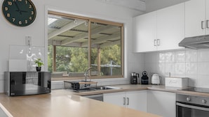 A modern kitchen with a large window, white cabinets, a built-in microwave, and a toaster. - Surf Beach Retreat, 200 mtrs from Surf Beach, family holiday games, free WiFi (Surf Beach)