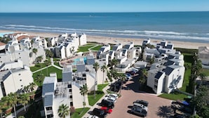 Ein Küstenresort mit moderner Architektur, einem zentral gelegenen Pool und Blick auf den Strand.
