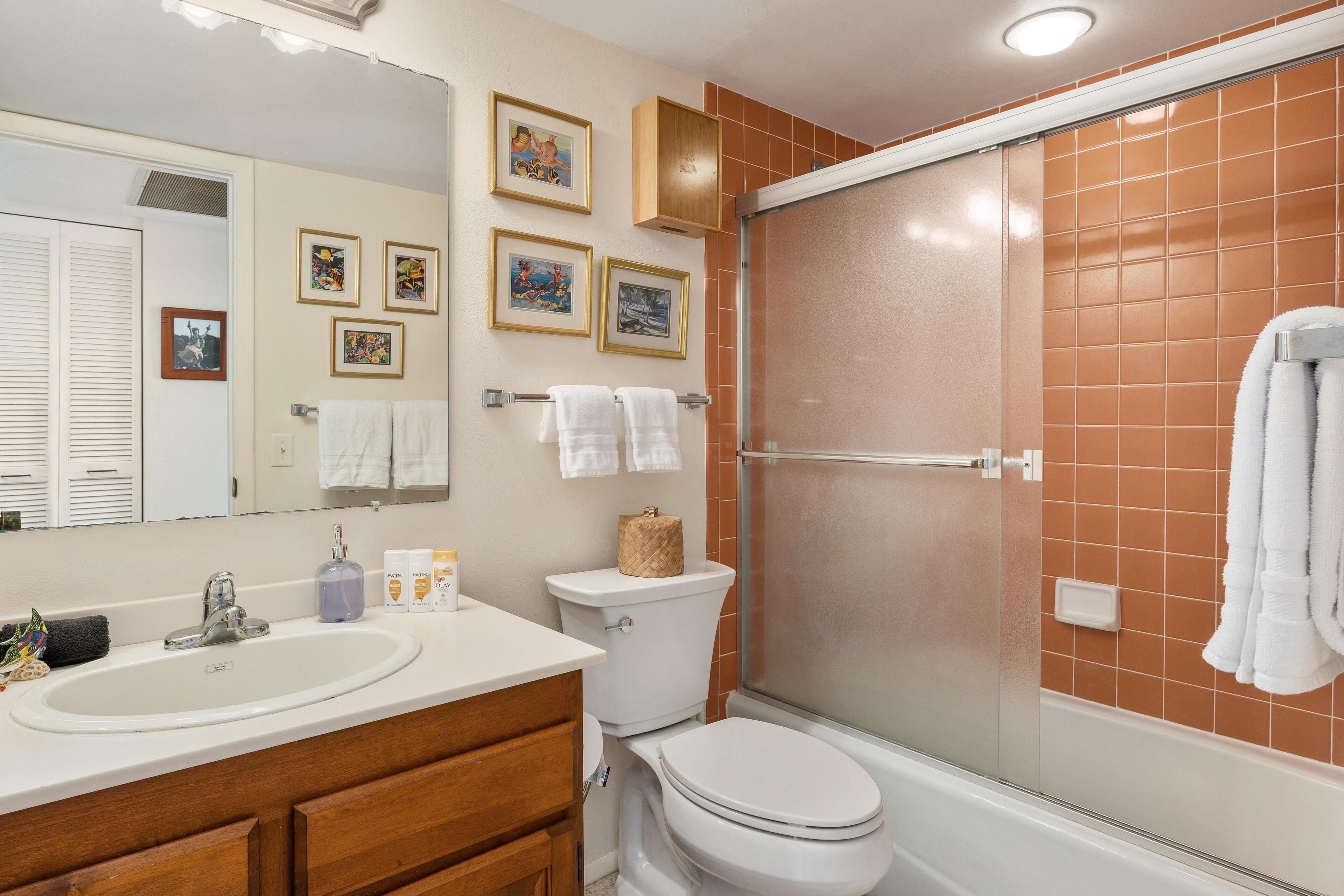 A bathroom with a sink, toilet, and shower area.