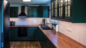A kitchen with dark green cabinets, a wooden countertop, and a black refrigerator. - Ganzes Haus für den Gruppen- und Familienurlaub (Klagenfurt am Wörthersee)