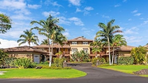 A multi-story hotel with a central courtyard, surrounded by palm trees and well-maintained lawns.