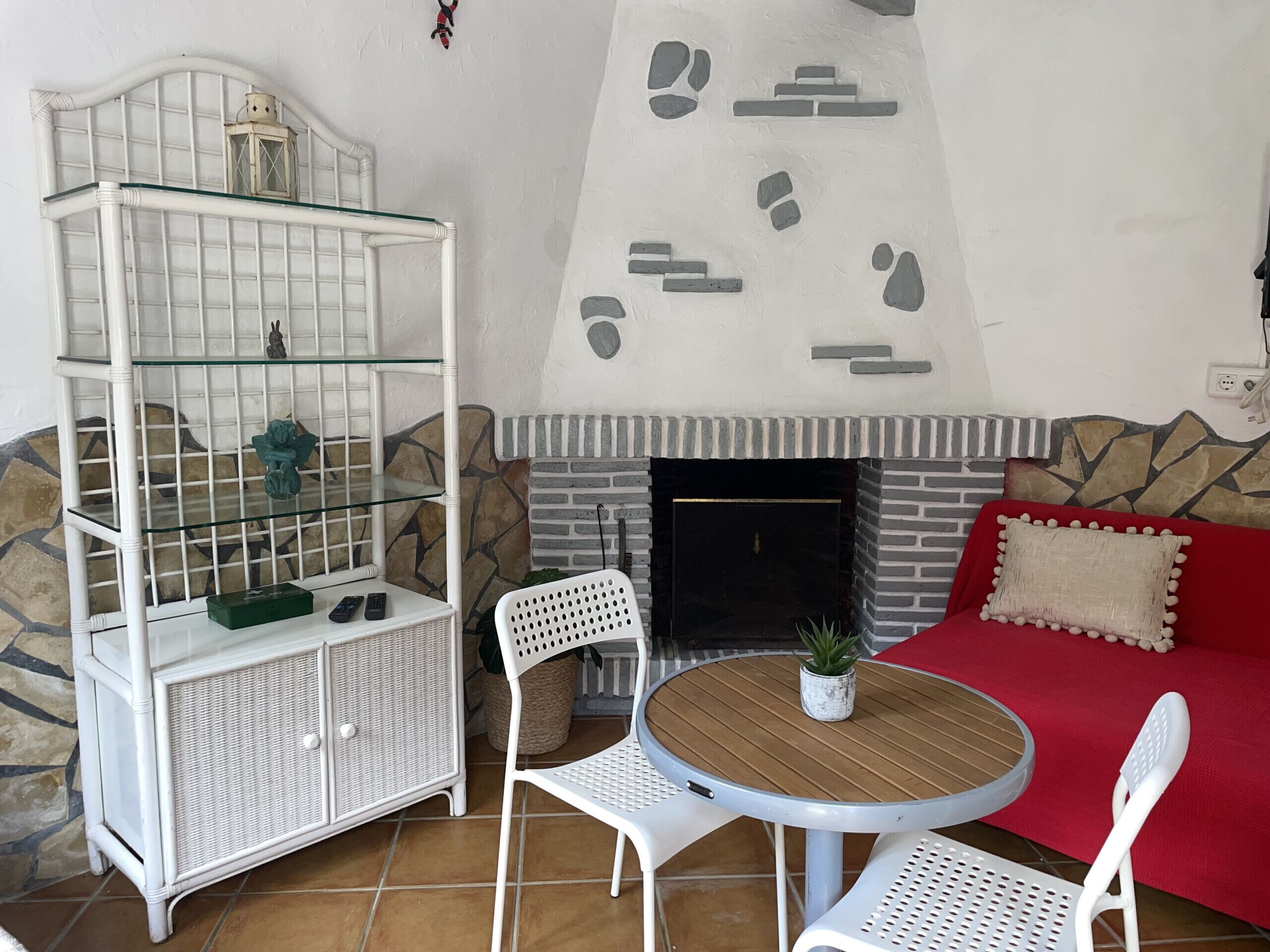Un salon doté d’une cheminée en pierre, de meubles blancs et d’un meuble vitrine en verre.