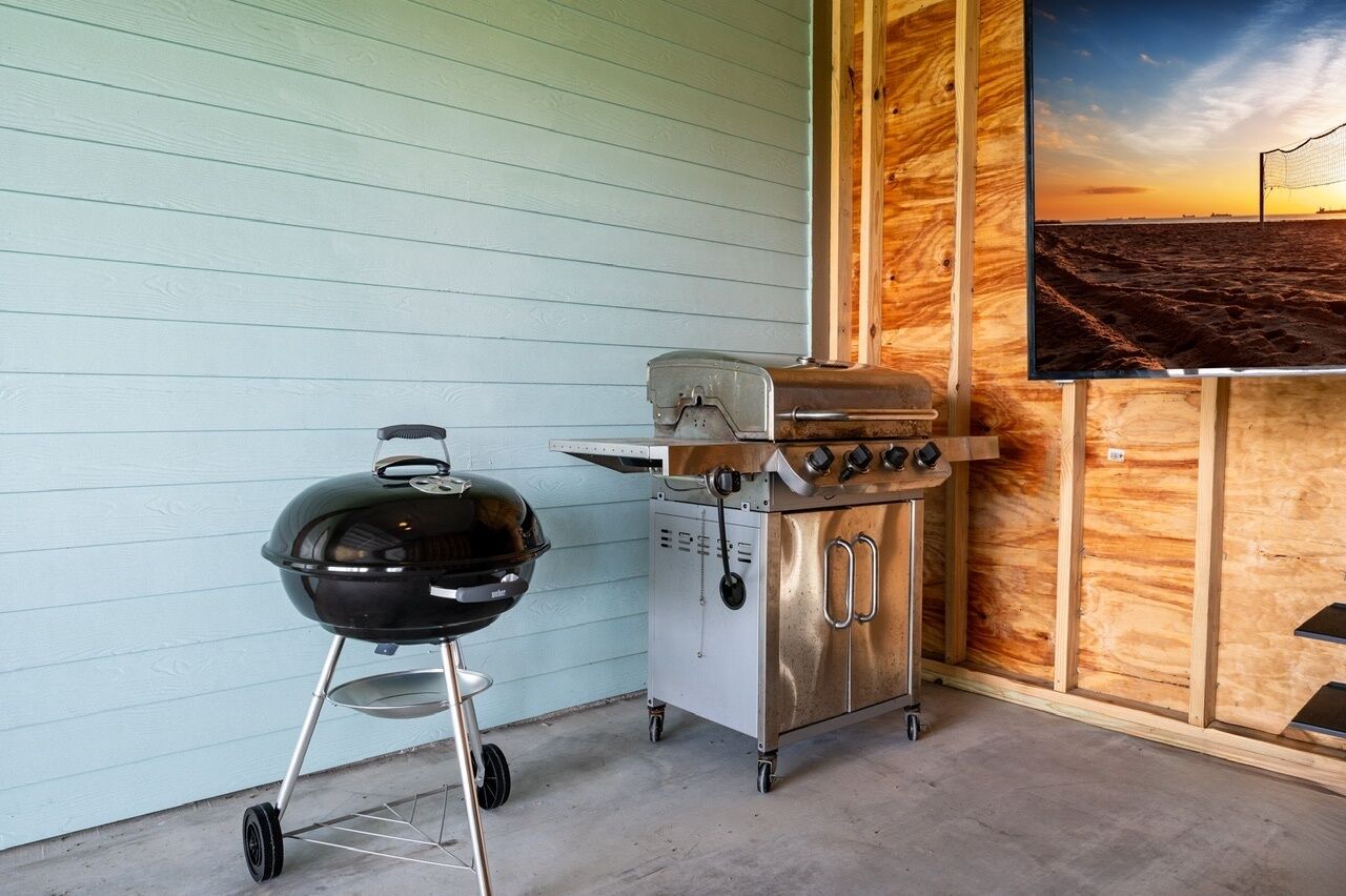 En grill klar til brug foran en lyseblå væg og en træpanel-væg.