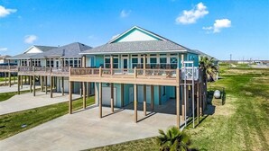 Un hôtel situé en bord de mer, avec plusieurs étages, des espaces de détente en plein air et une zone abritée.