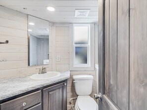 A bathroom with a wooden vanity, a sink, a mirror, and a toilet. - Tequila Sunrise Sfth6 1 Bedroom Cottage by RedAwning (Port Aransas)