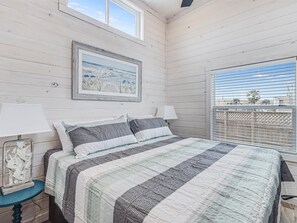 Relax in this serene bedroom with a large bed, a framed painting, and a window offering a view of the outside.