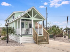 Stroll up the covered porch to the entrance of this charming two-story home, surrounded by lush tropical gardens and a gravel driveway.