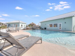 Relax by the resort pool surrounded by a white fence and lounge chairs.
