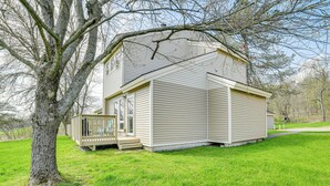 Een gelijkvloers huis met een veranda en een klein terras, omgeven door een gazon.
