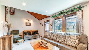 Een gezellige woonkamer met een houten salontafel, een grijze bank, een groene fauteuil en een klein houten kastje.