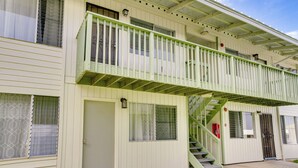 A two-story building with a green balcony and a staircase leading to the upper floor.