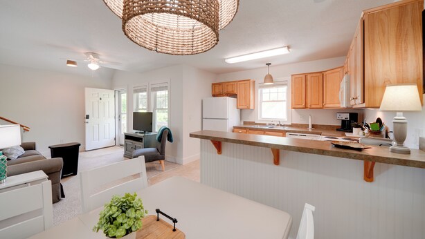 A modern kitchen with wooden cabinets, a central island, and a hanging light fixture. - Buxton Vacation Rental w/ Shared Canal Access! (Buxton)