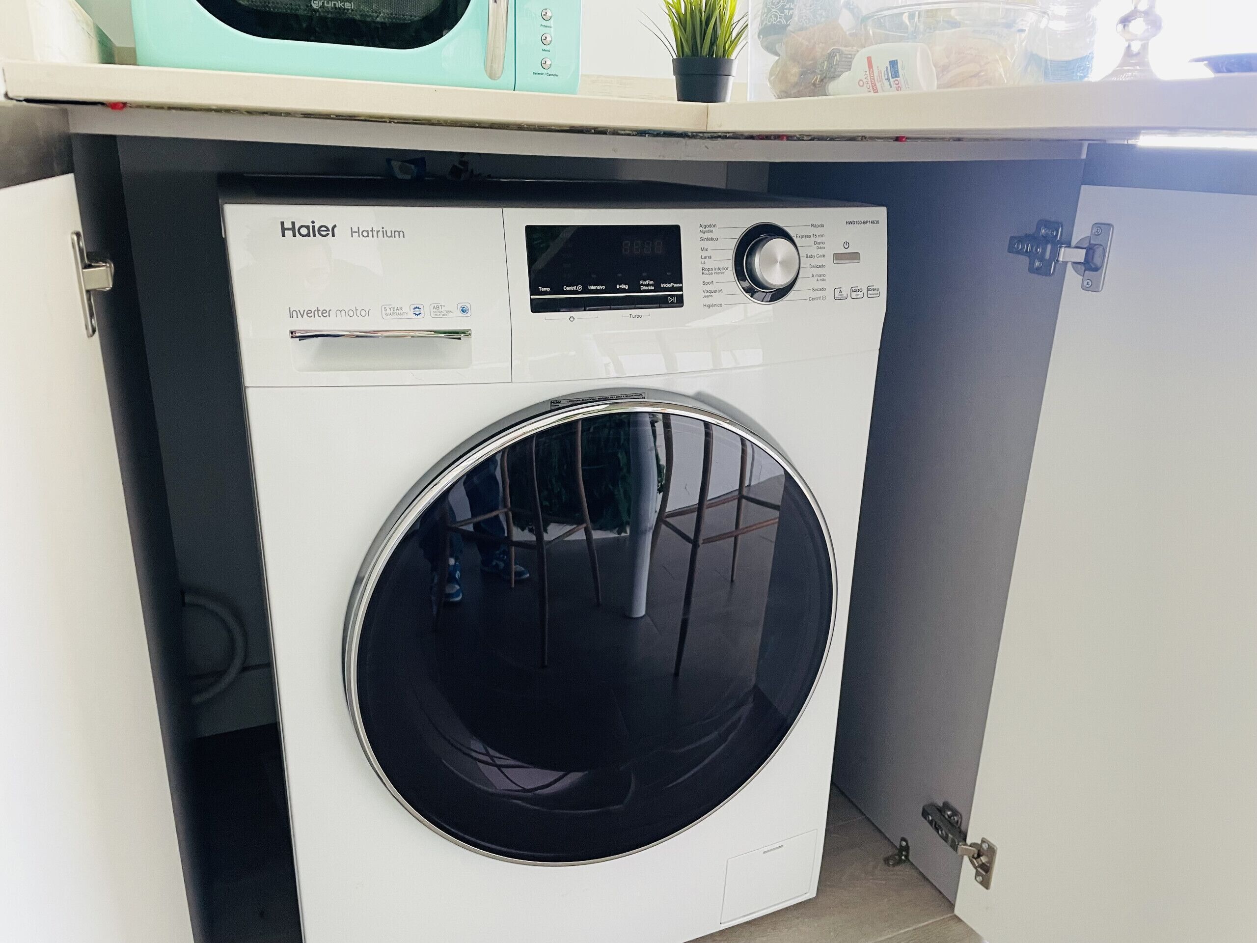 Een wasmachine en droger met voorlader, een bedieningspaneel en een ronde deur.