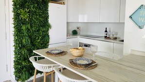 A modern kitchen with white cabinets, a wooden table set for two, and a vertical garden wall. - Dunas Beach with sea views in Torrox Costa (Torrox Costa)