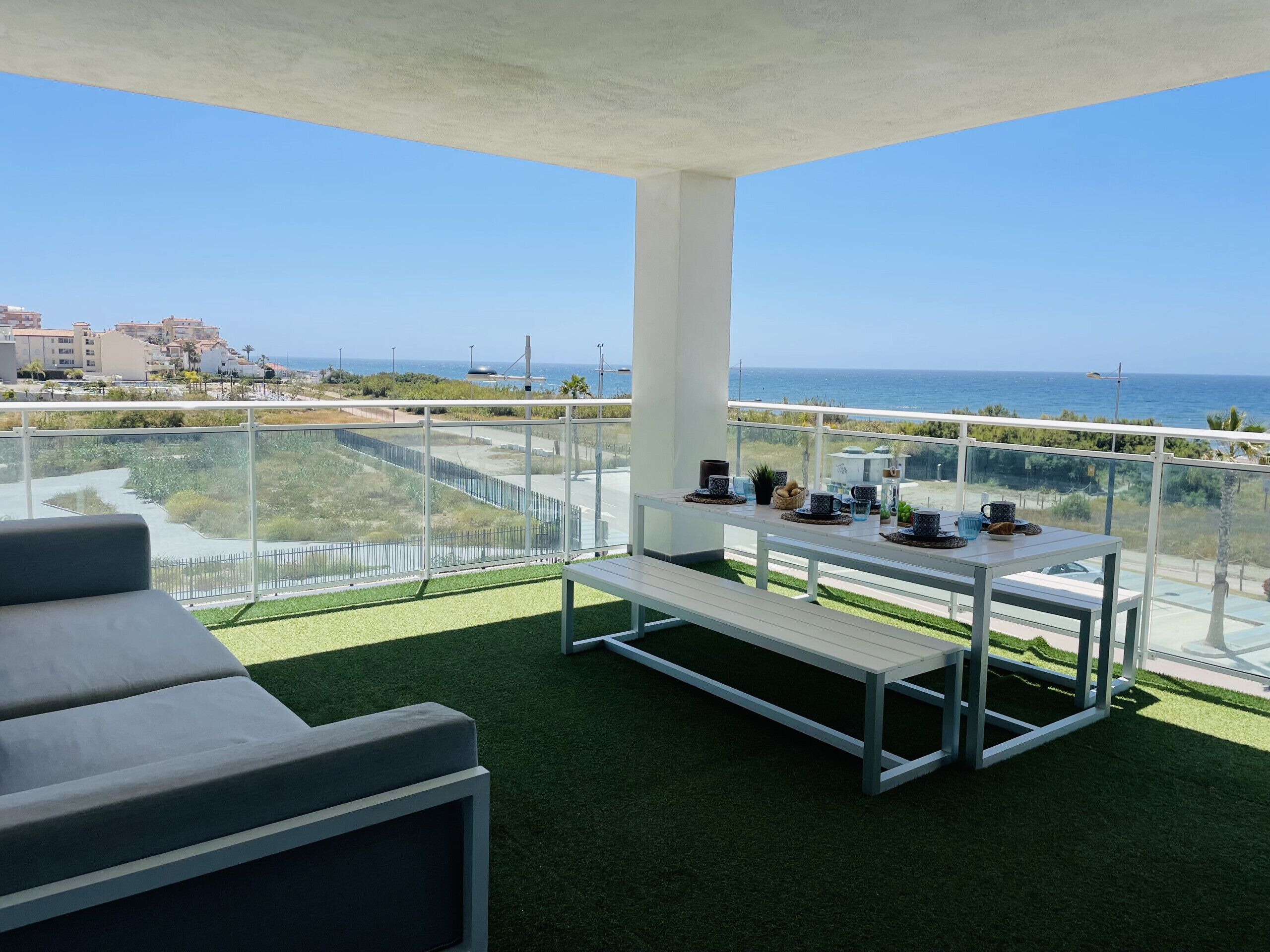 Un balcon avec vue sur la mer, une table avec des tasses et un banc.