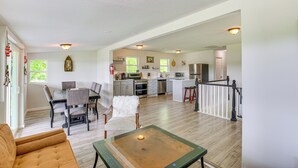 Un vaste salon comprenant un coin repas, une cuisine et un escalier menant à un autre niveau.