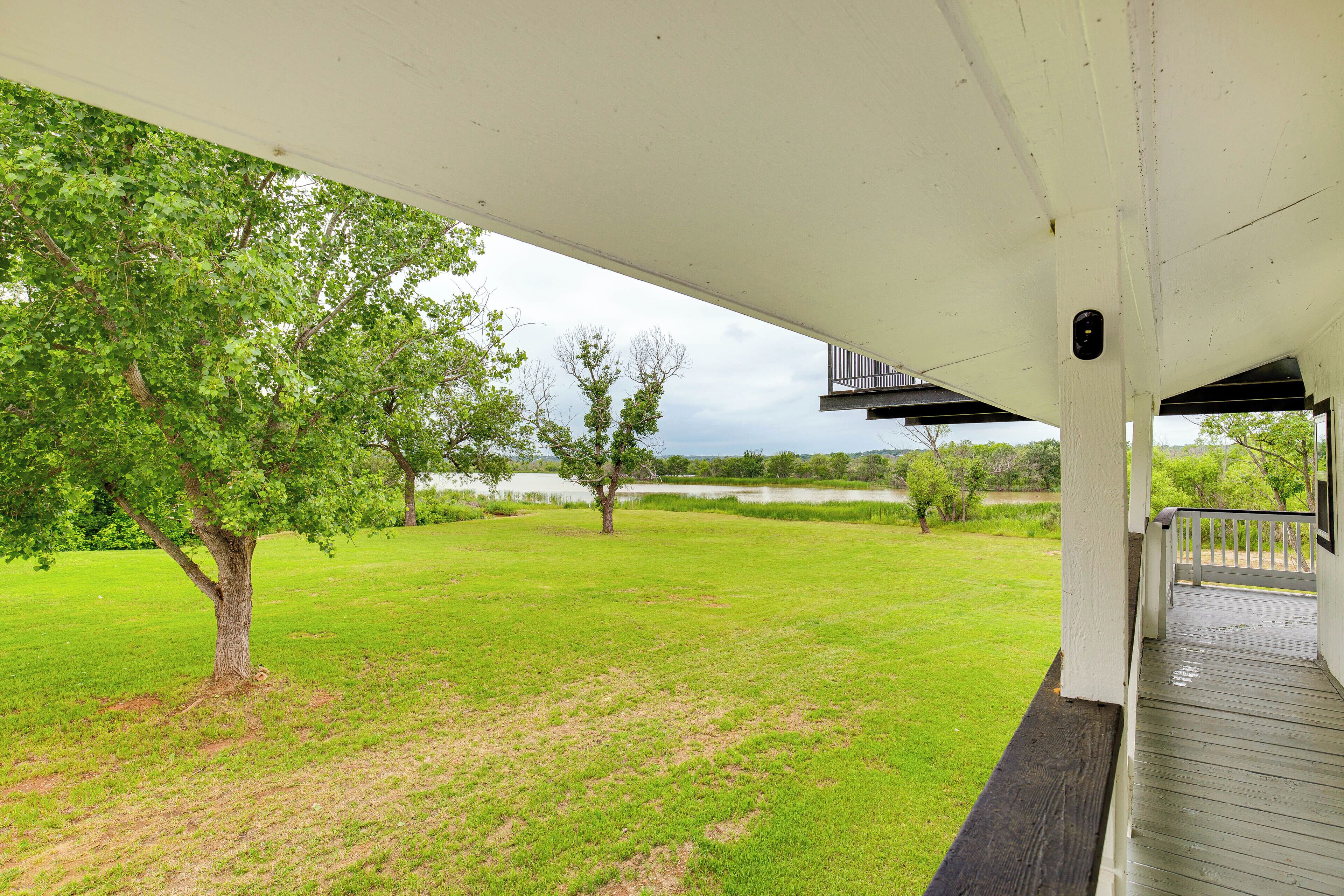 A covered porch with a view of a grassy area and trees.