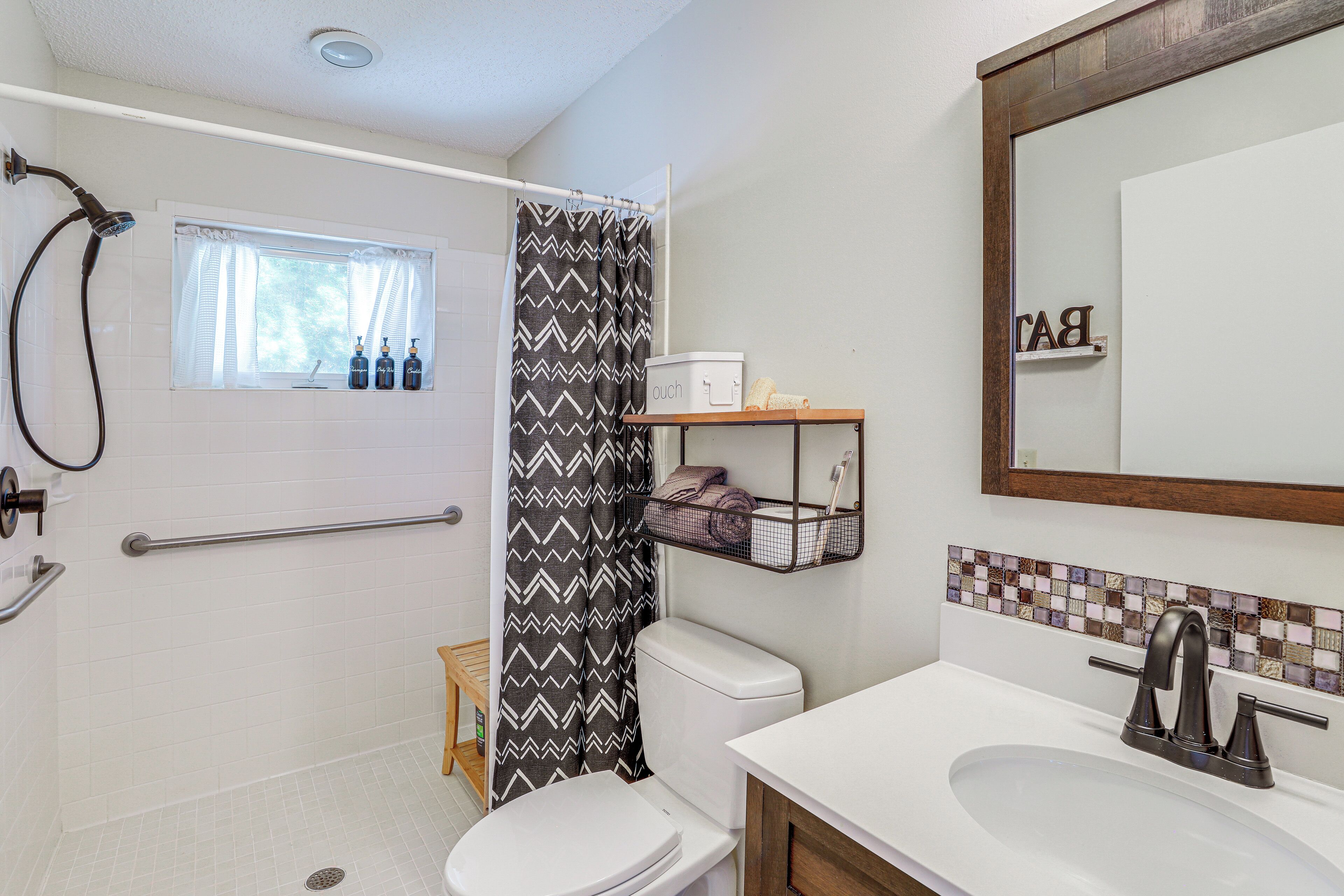 Ein Badezimmer mit Dusche, Toilette, Waschbecken und einem Fenster mit Vorhang.