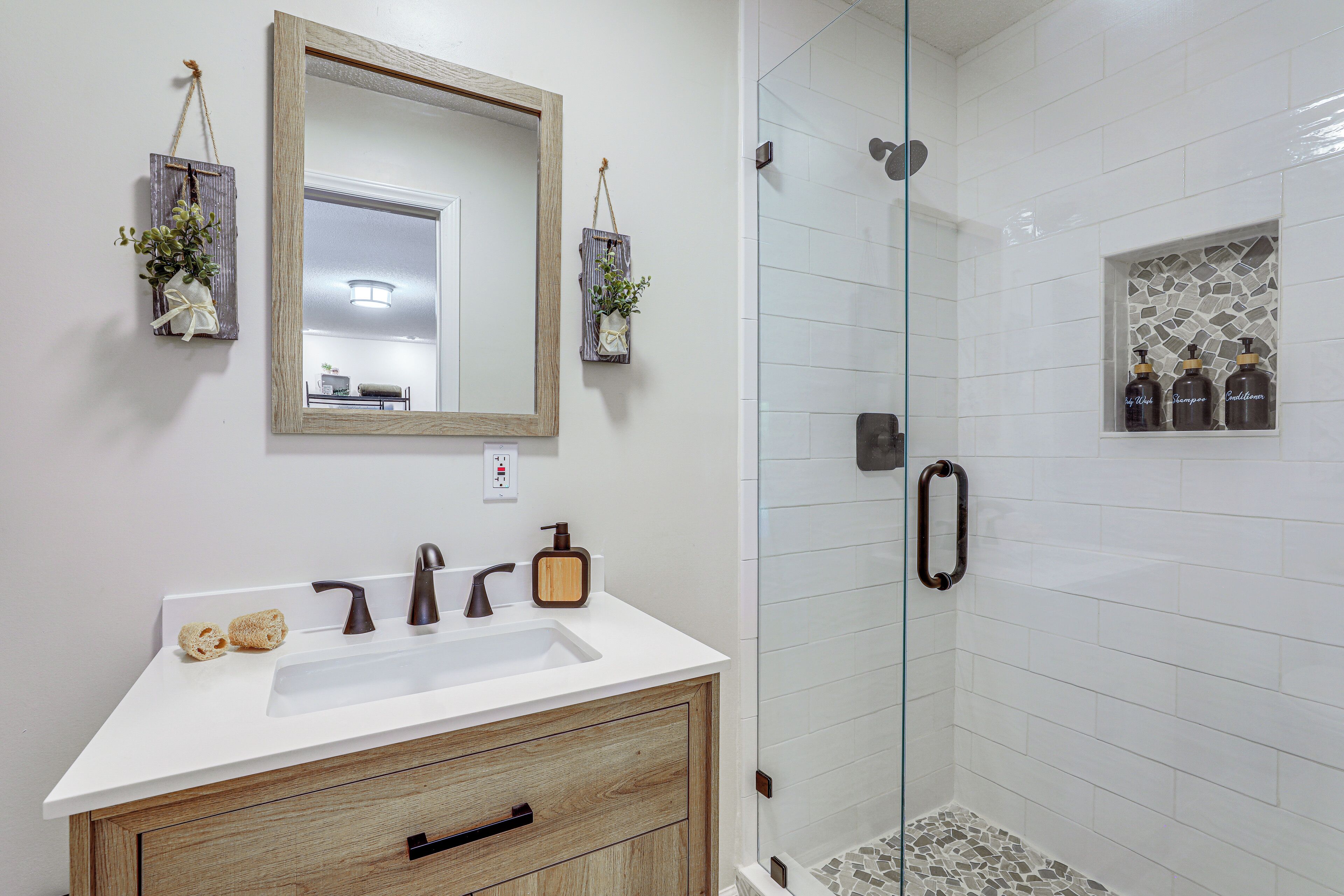 Une salle de bain avec un lavabo blanc, un meuble-lavabo en bois et une cabine de douche en verre.