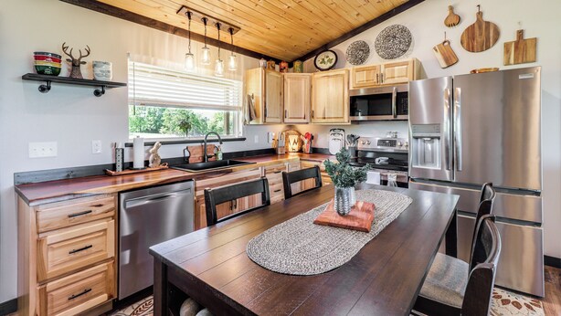 A modern kitchen with wooden cabinets, stainless steel appliances, and a wooden dining table.