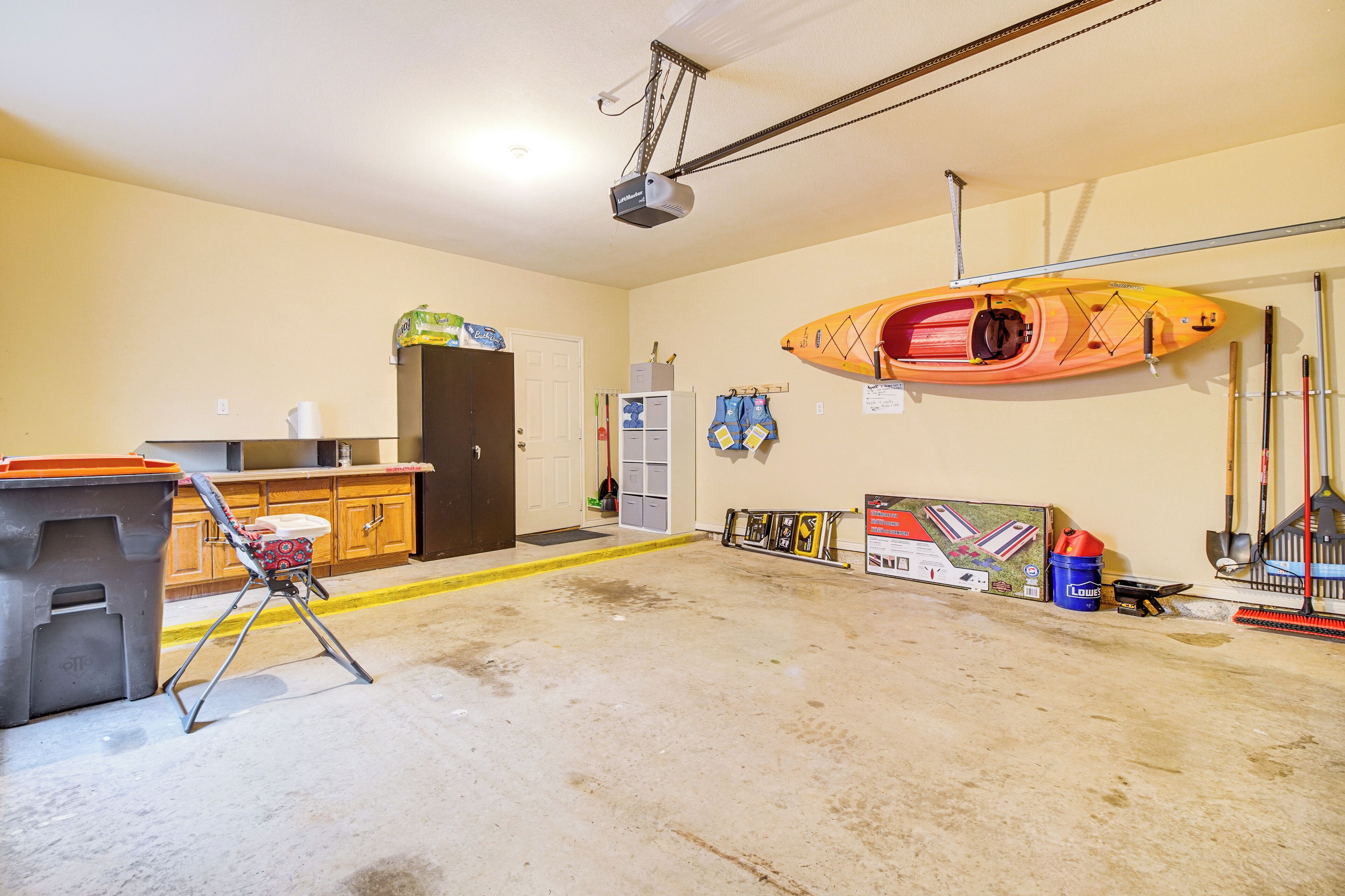 A garage with a kayak, fishing rods, and a projector mounted on the ceiling.