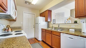 Une cuisine avec des meubles de rangement en bois, un réfrigérateur blanc, une cuisinière et un lave-vaisselle.