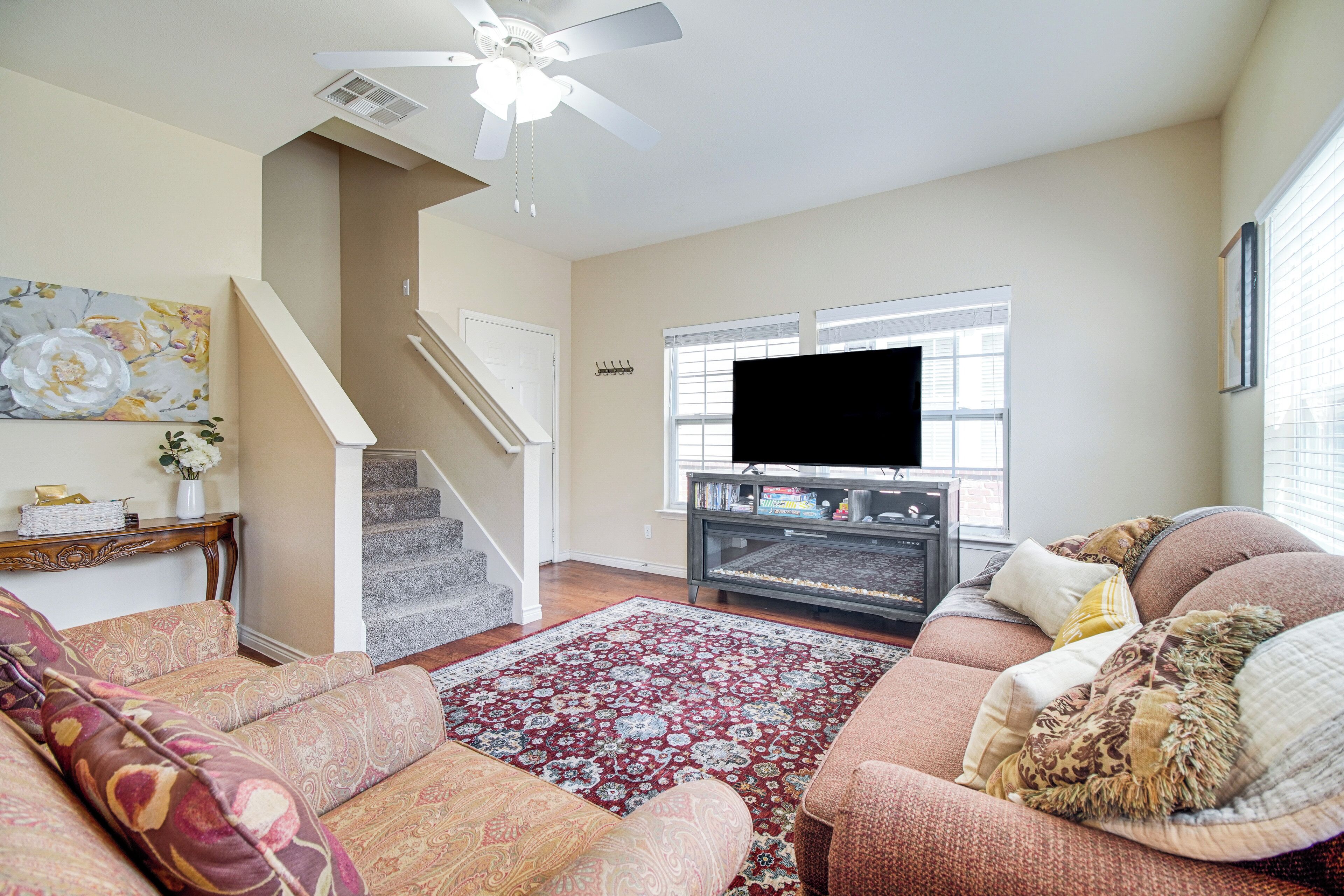 A living room with a sofa, a coffee table, a TV, a fireplace, and a staircase.
