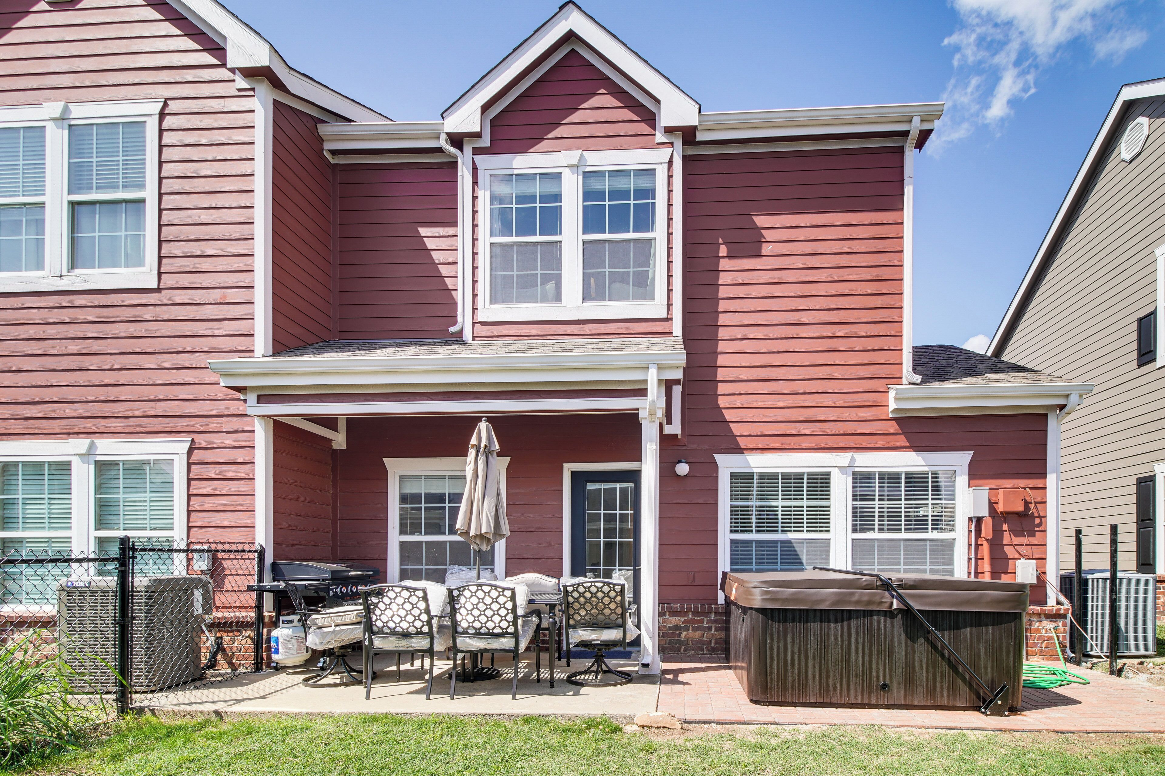 A two-story house with a covered patio area featuring a grill, outdoor seating, and a hot tub.