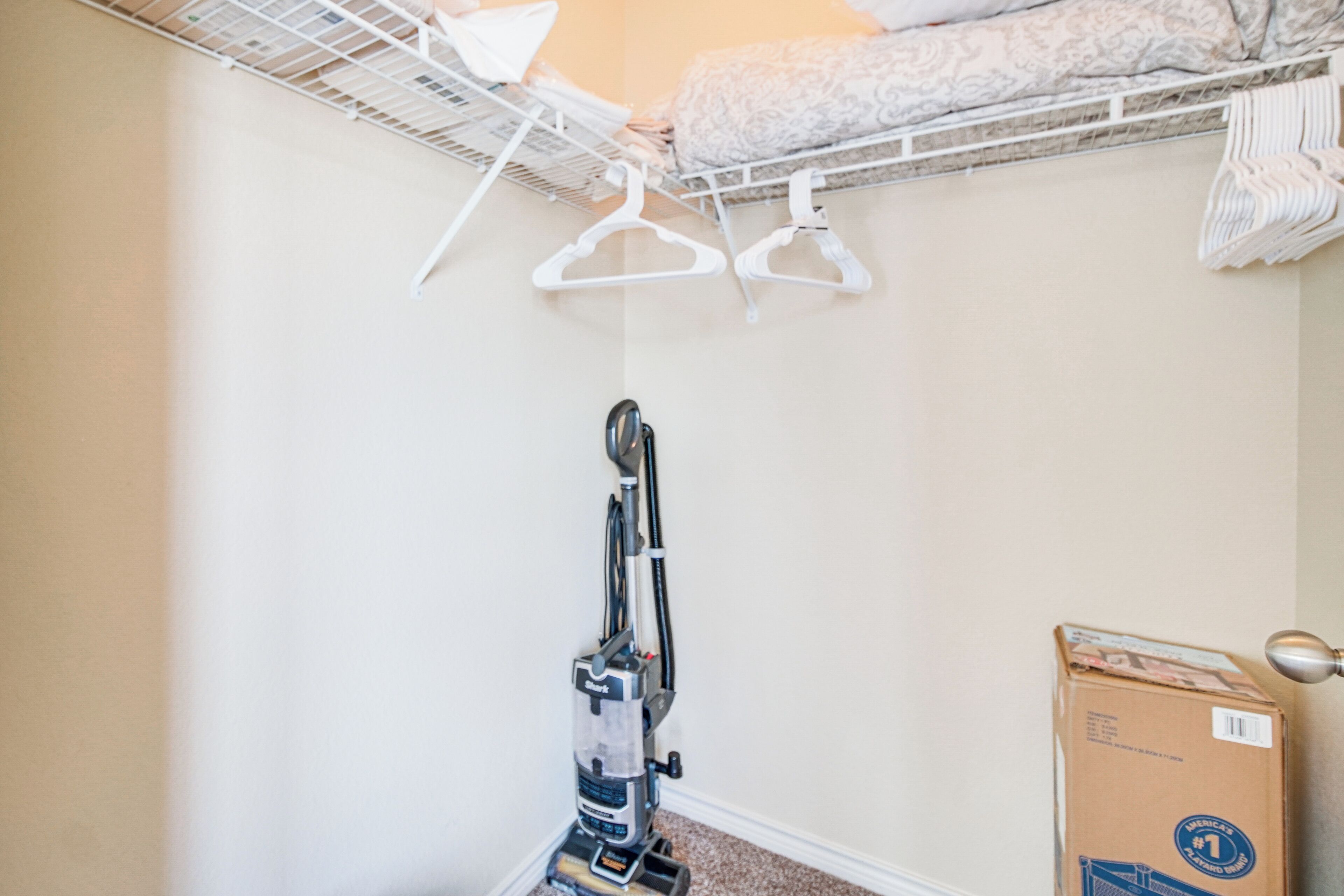 Une pièce avec un lit superposé, un aspirateur et une boîte en carton.