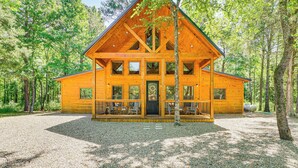 A log cabin with a porch, multiple windows, and a gravel driveway. - Private Hot Tub: Luxe Cabin in Broken Bow! (Broken Bow)