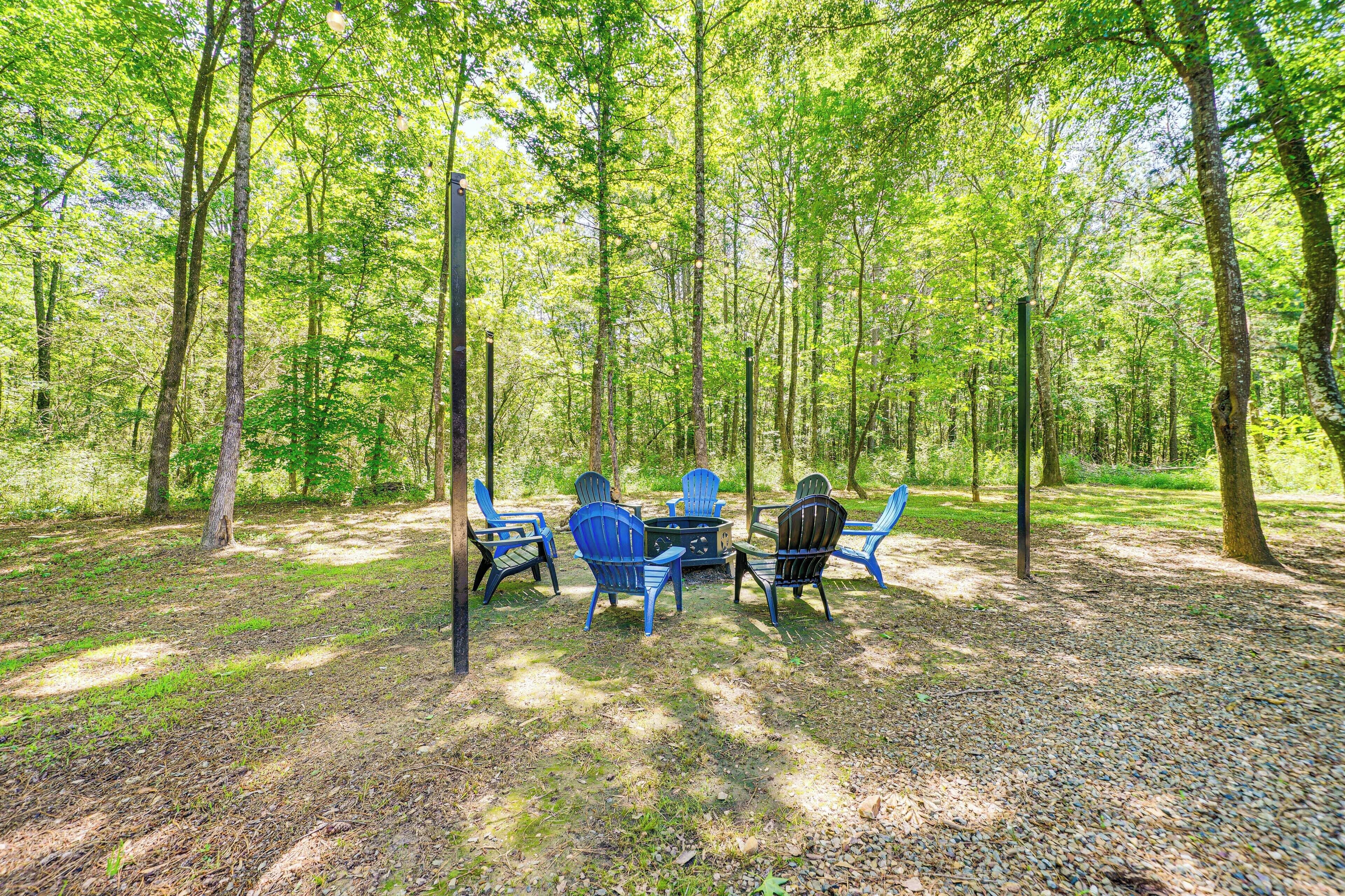 Un espace extérieur aménagé avec des chaises bleues et une table, situé dans un cadre forestier.