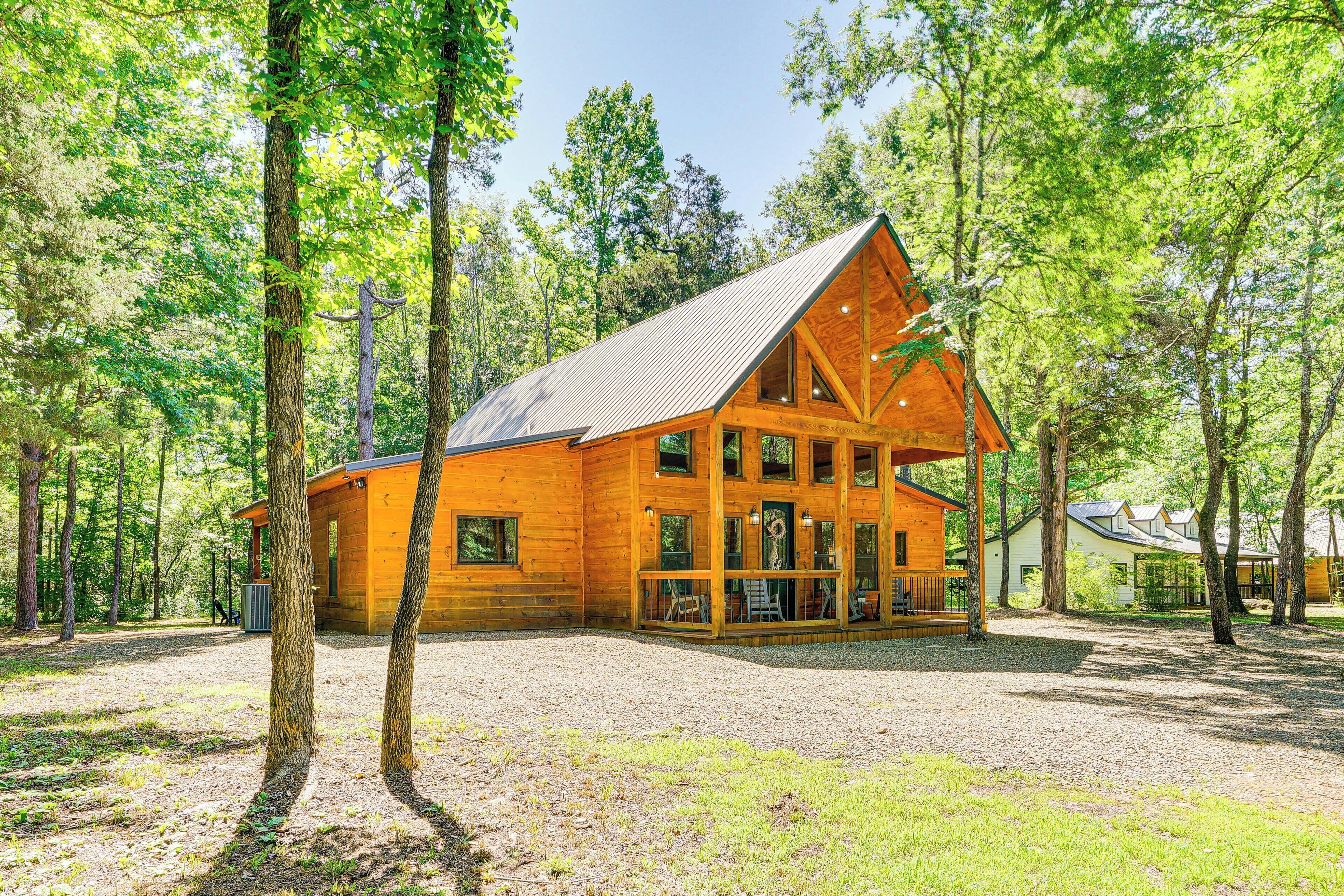 A wooden cabin with a large porch, surrounded by trees.