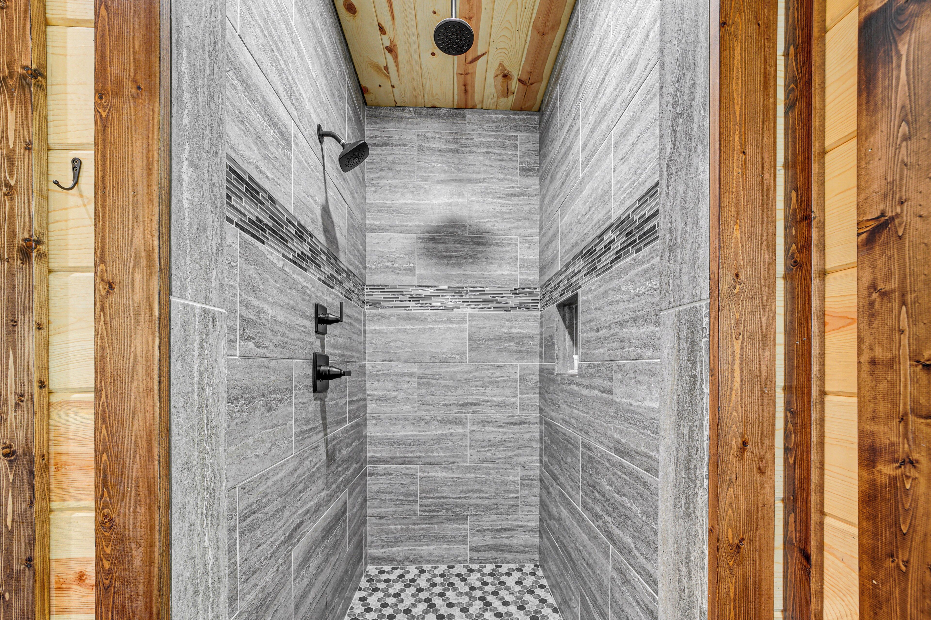 A narrow shower with wooden walls and a tiled floor.