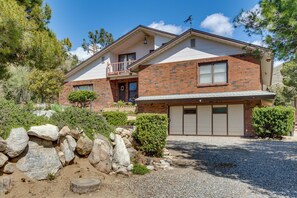 Set amidst a natural environment, this two-story house offers a front porch and a garage, surrounded by a well-maintained yard with landscaping and trees.