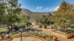 A landscaped garden with a variety of trees and shrubs, a paved patio area, and a view of distant mountains. - Beautiful Kernville Home w/ Game Room & Mtn Views! (Kernville)