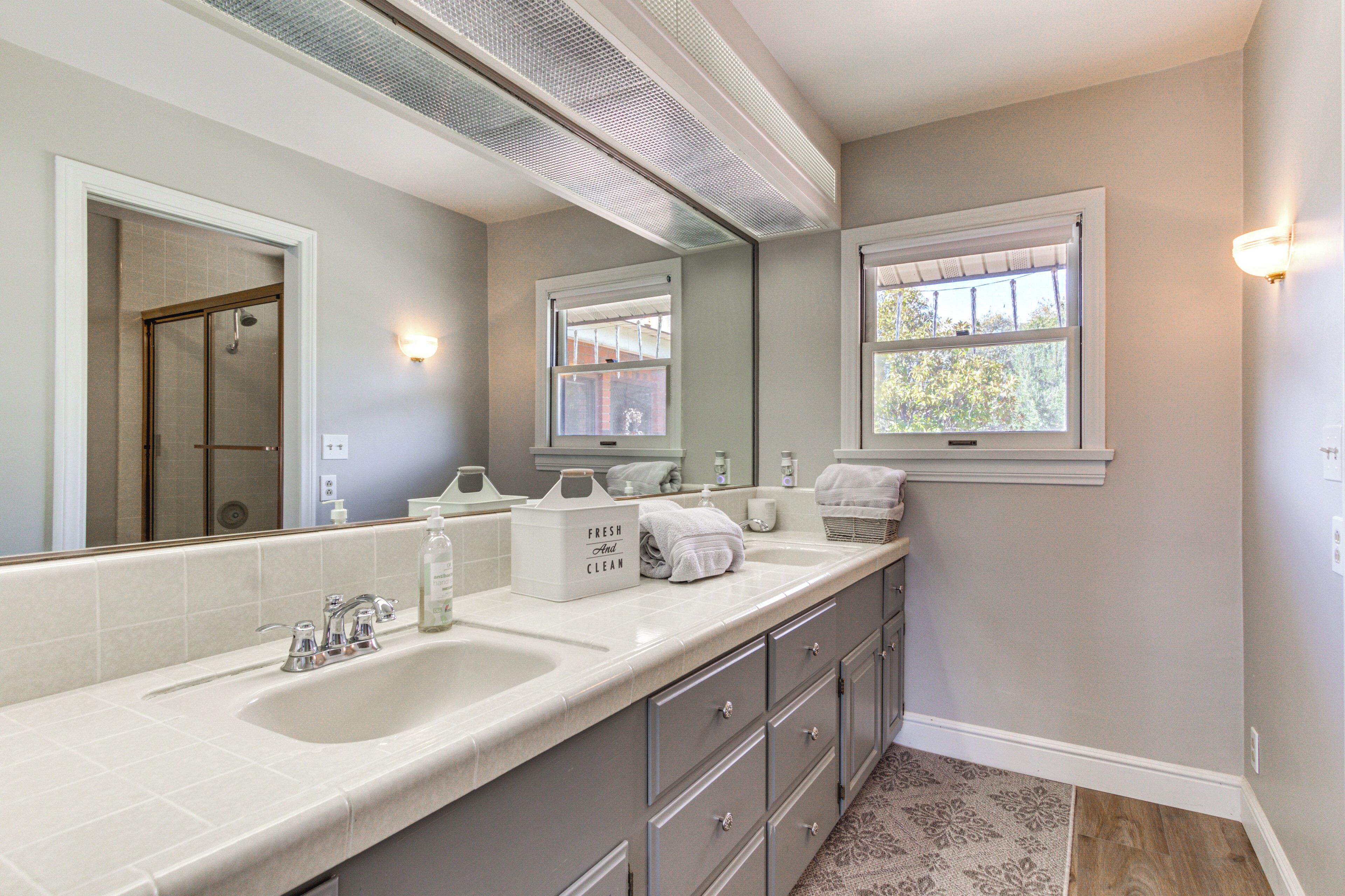 A bathroom with a double sink, a large mirror, and a window.